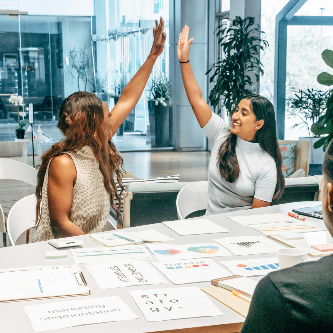Two diverse female professionals giving a high-five in a modern office, celebrating a successful marketing strategy discussion. The workspace is filled with strategy documents, charts, and collaborative energy, reflecting teamwork, innovation, and workplace empowerment."
This ALT text aligns with KimUnity Solutions' brand values while incorporating SEO-friendly keywords such as "teamwork," "marketing strategy," "collaboration," "innovation," and "workplace empowerment.